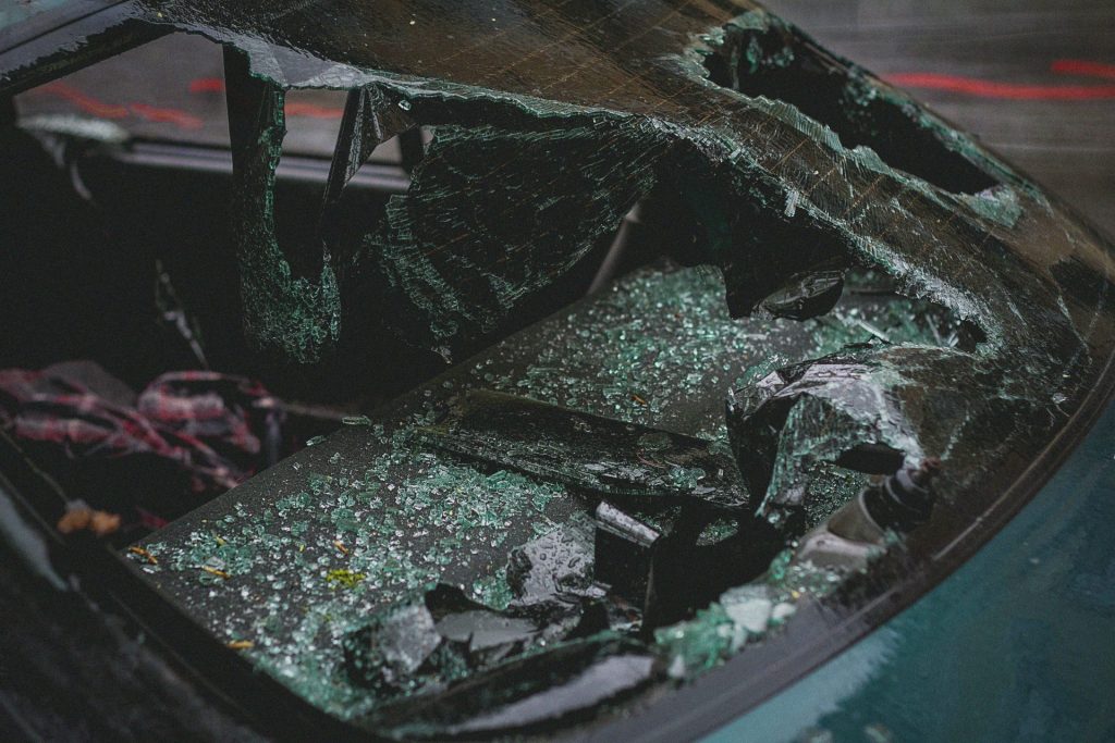 Detailed view of shattered car windshield after accident, emphasizing damage and broken glass.