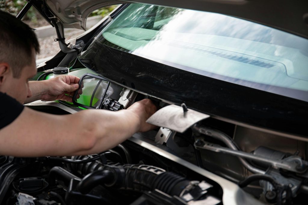 A mechanic working on car maintenance. Close-up of hands fixing vehicle engine.