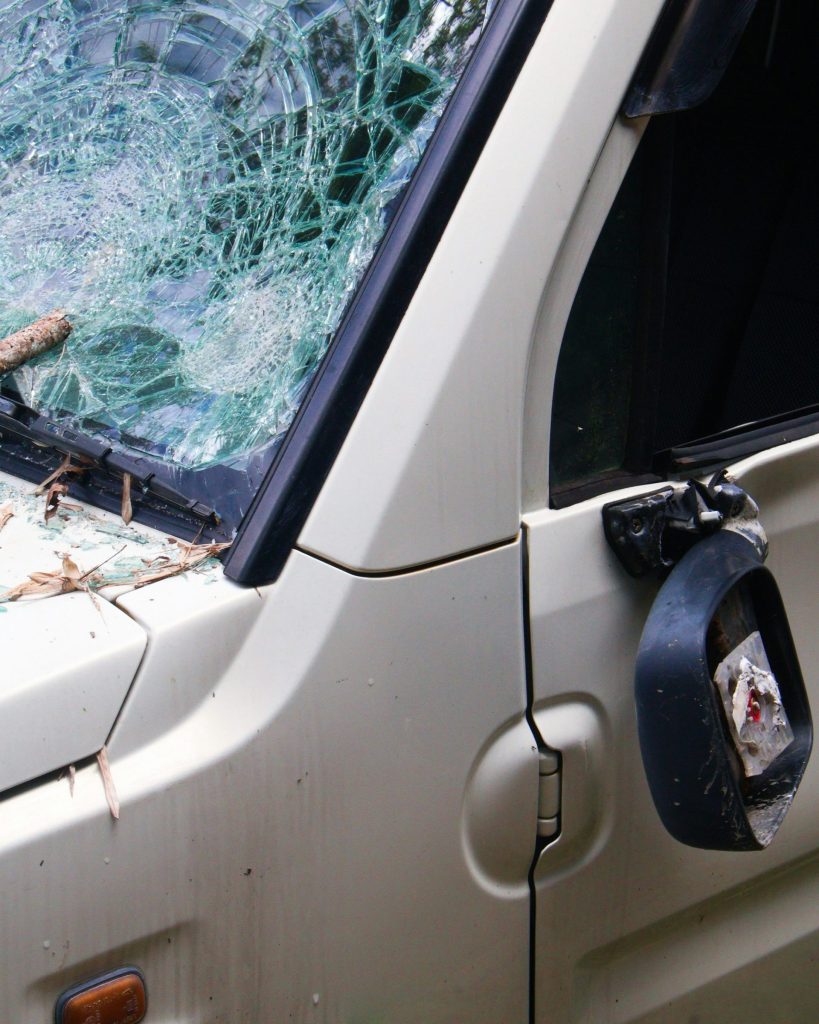 Damaged car with shattered windshield and broken mirror.